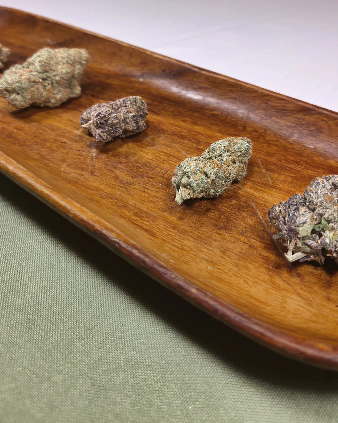 several cannabis flower varieties arranged on a wooden tray