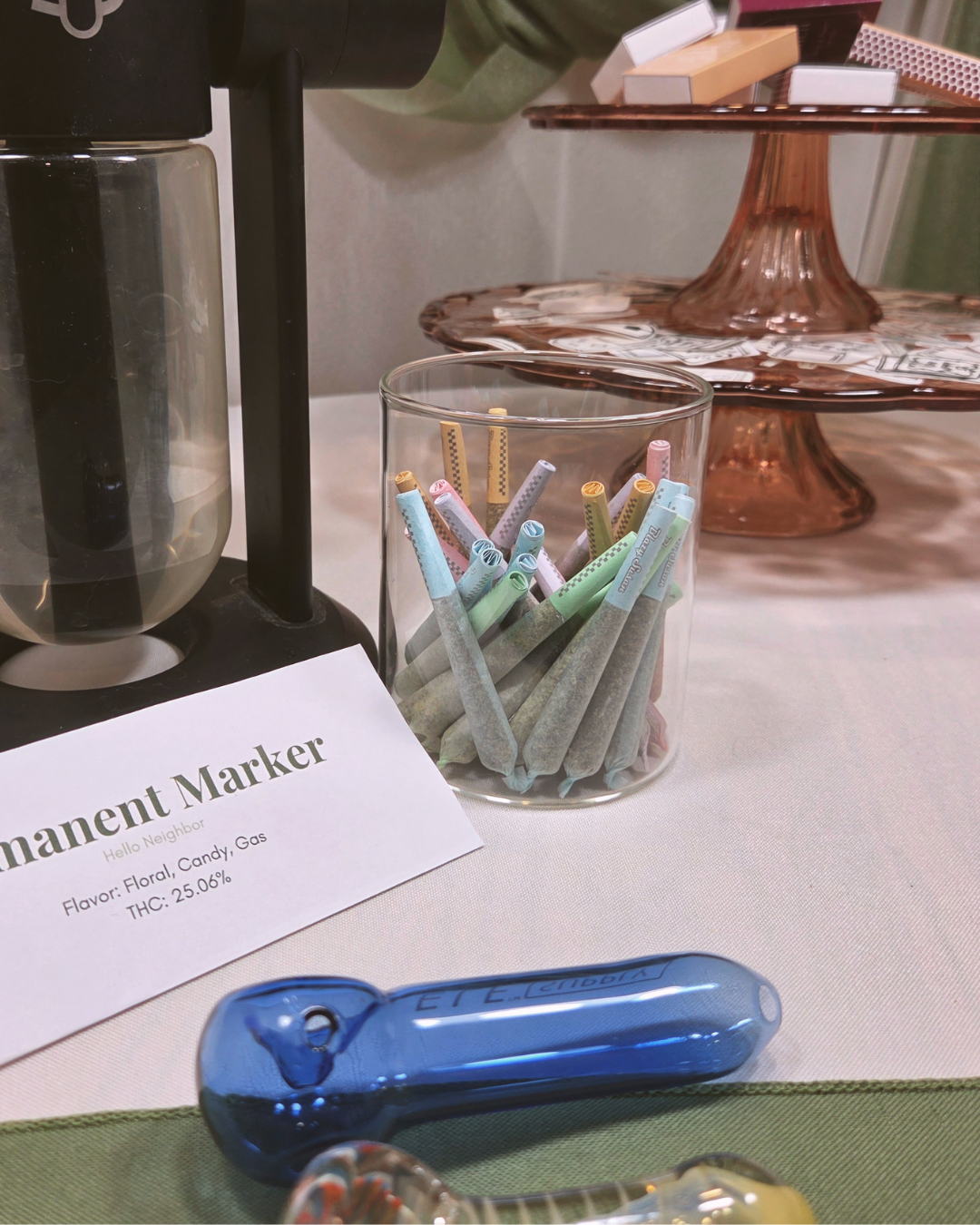 colorful pre-rolls, blue glassware, a serving device, and a cannabis menu card